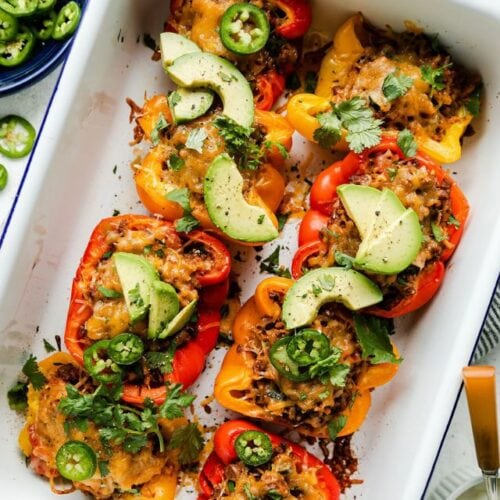 Overhead view white baking dish filled with lined up taco stuffed bell peppers