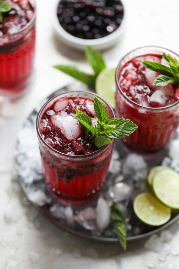 Overhead view blueberry mojitos in tall glasses with fresh mint sprigs.