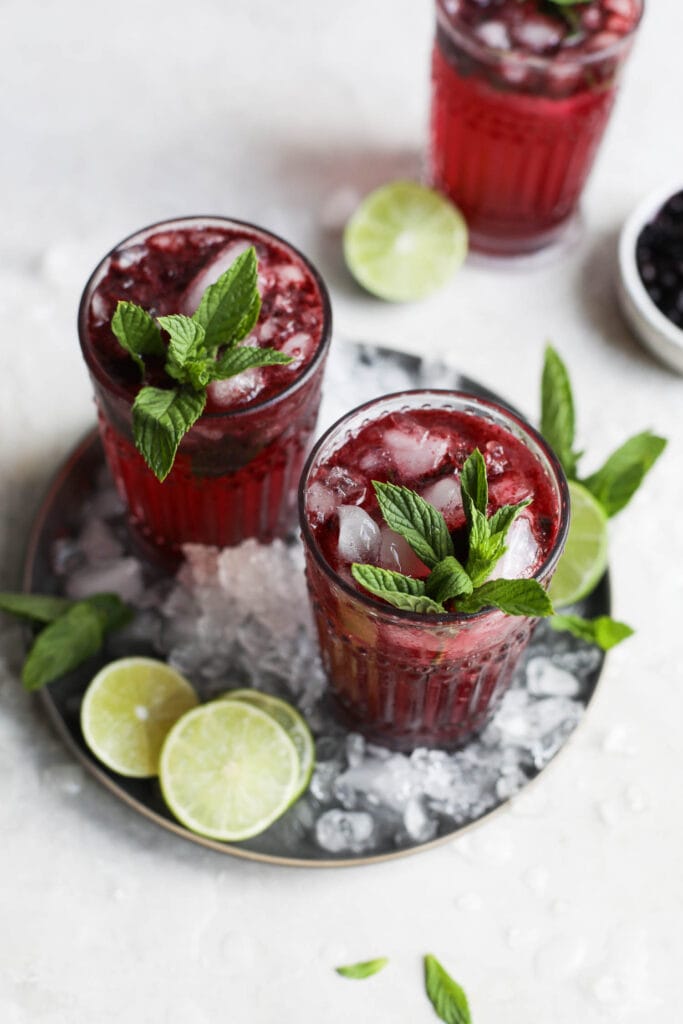 Overhead view blueberry mojitos in tall glasses with fresh mint sprigs as garnish