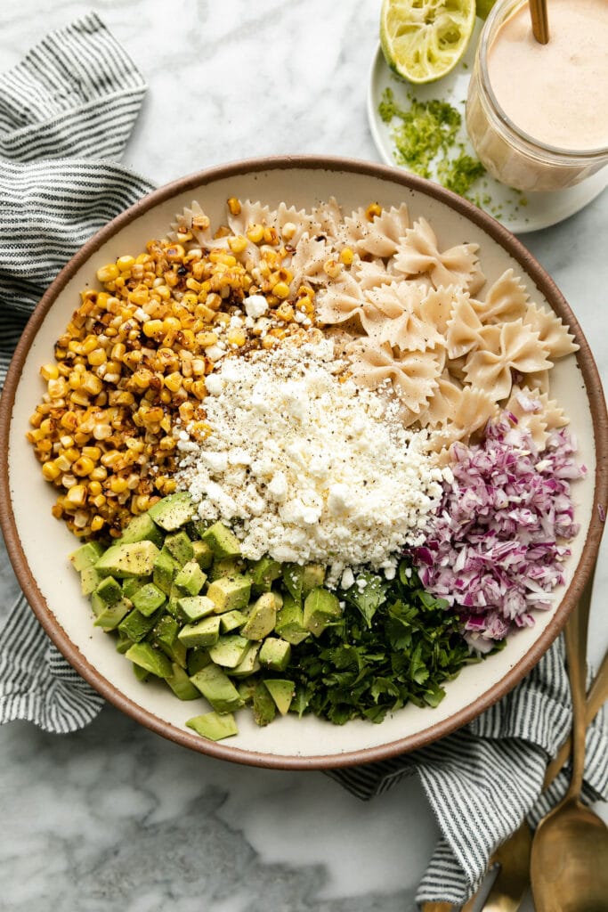 All ingredients in stone serving bowl for Mexican Street Corn Pasta Salad ready to be mixed together.