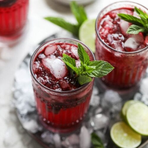 Overhead view tall glasses of blueberry mojito garnished with fresh mint