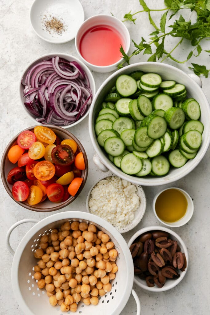 All ingredients for Greek cucumber salad arranged in small bowls