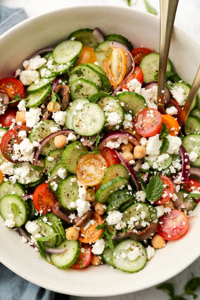 Close up view Greek cucumber salad in serving bowl topped with crumbled feta cheese