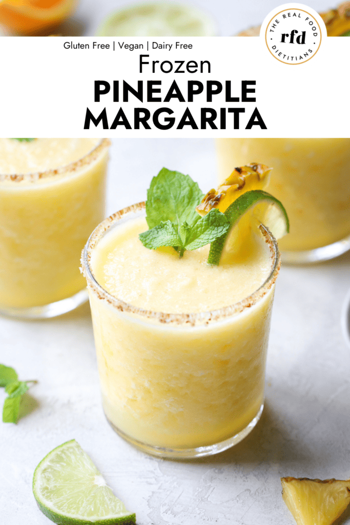 short glasses filled with frozen pineapple margarita, garnished with fresh mint, pineapple chunk and fresh mint.
