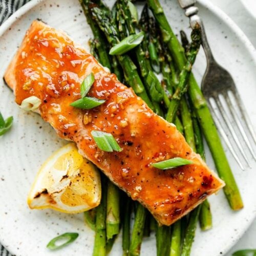 Overhead view honey glazed salmon with asparagus on white plate