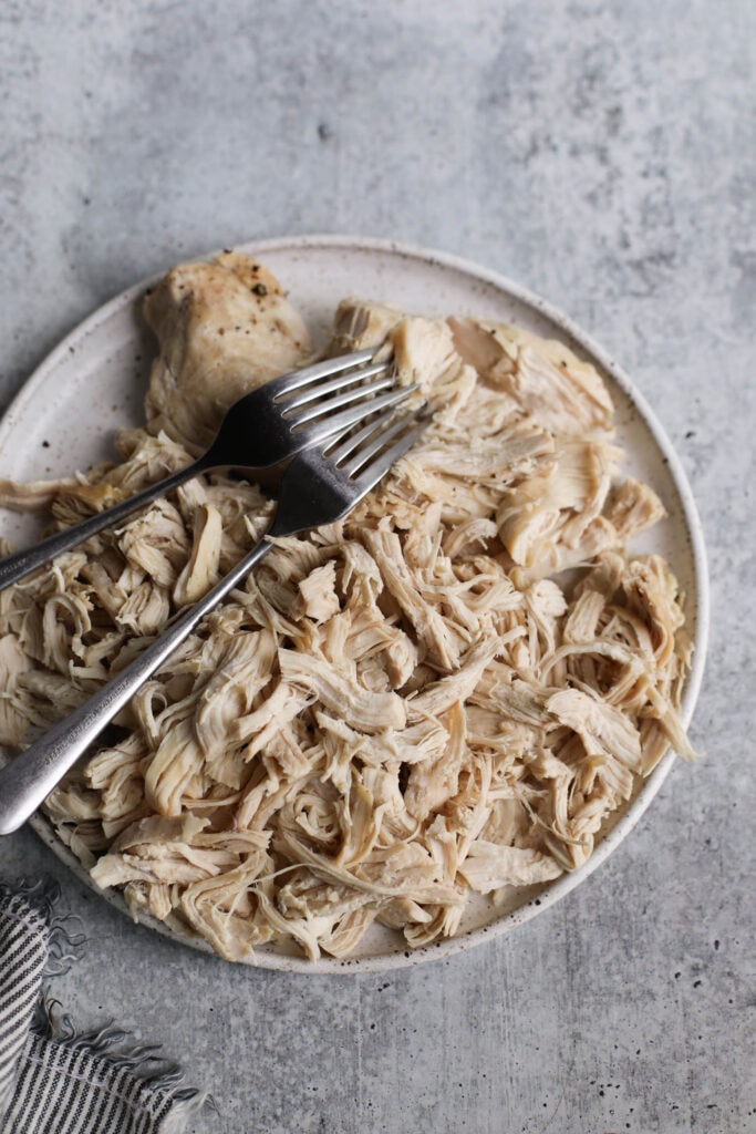 Stone plate with Instant Pot Shredded Chicken, two forks on shredded chicken
