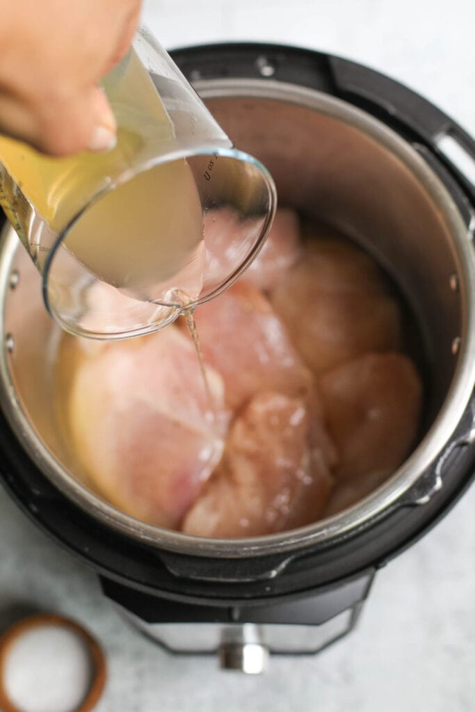Broth being added to chicken breast to keep Instant Pot shredded chicken moist.