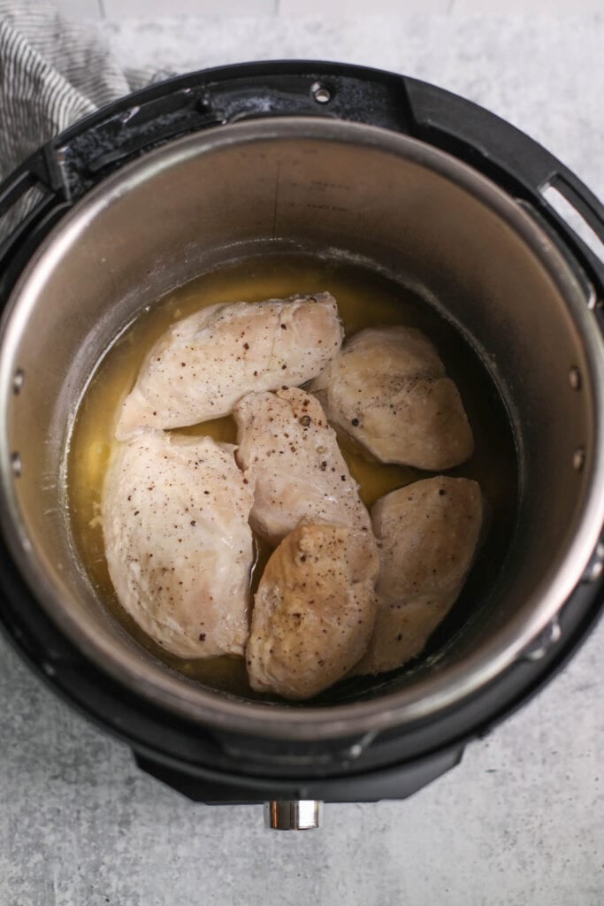 An overhead view of the cooked chicken breast in the Instant Pot, ready to be shredded. 