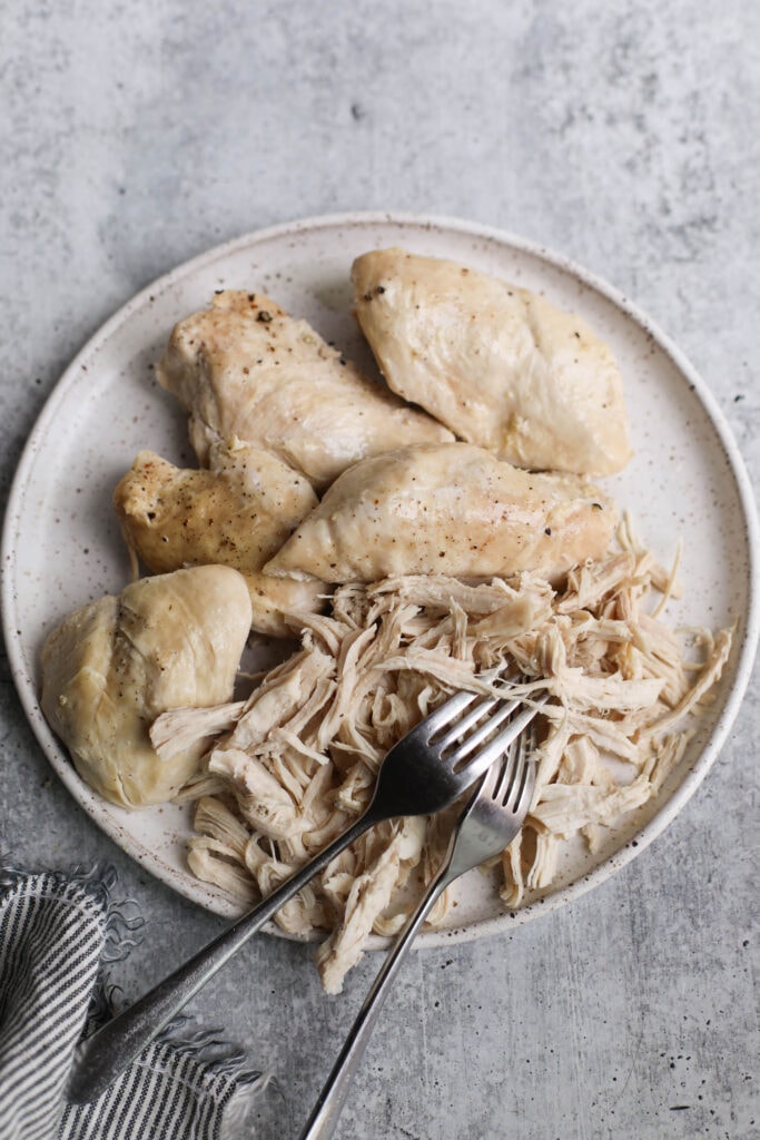 Instant Pot Chicken breasts on stone plate being shredded with two forks.