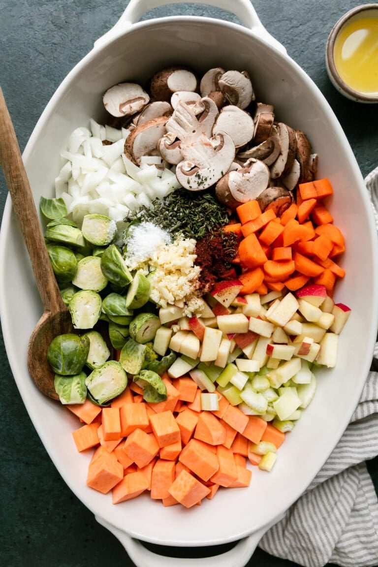 Overhead view white casserole dish filled with fresh cut vegetables and root vegetables