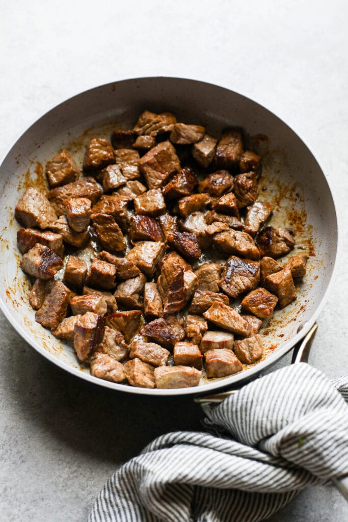 Cooked beef pieces in white bowl for beef and lentil stew