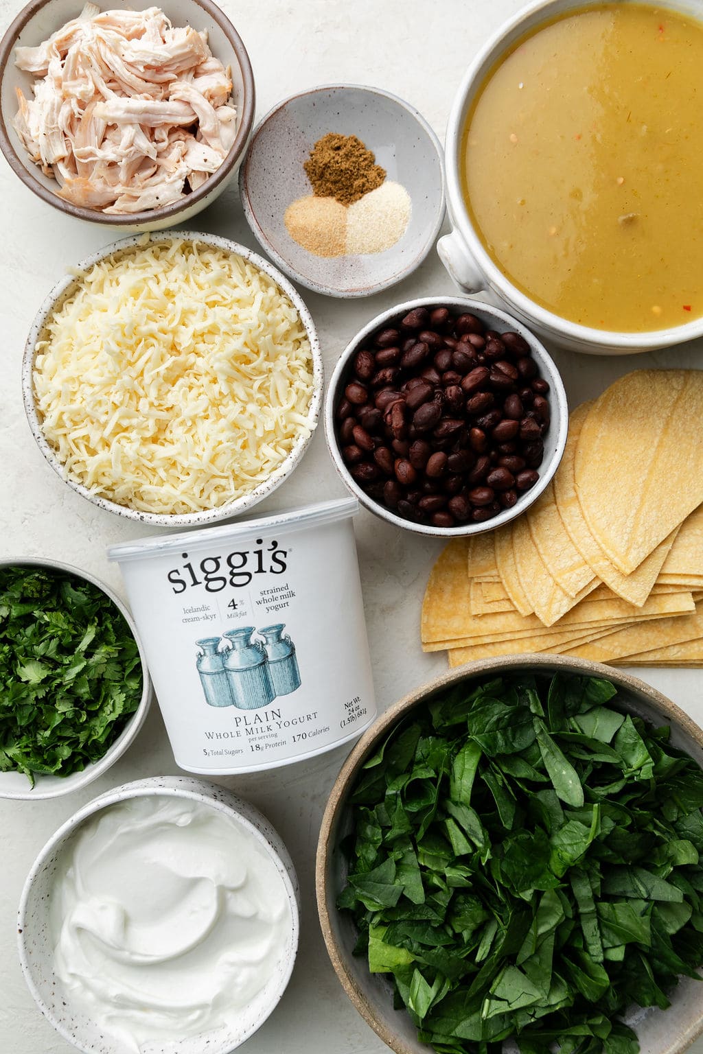 All ingredients for green chicken enchilada casserole in small bowls.