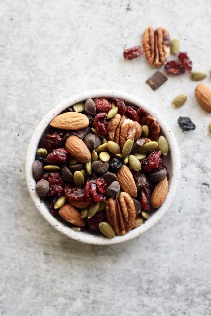 Overhead view small stone bowl filled with trail mix with almonds and dark chocolate for healthy snacks