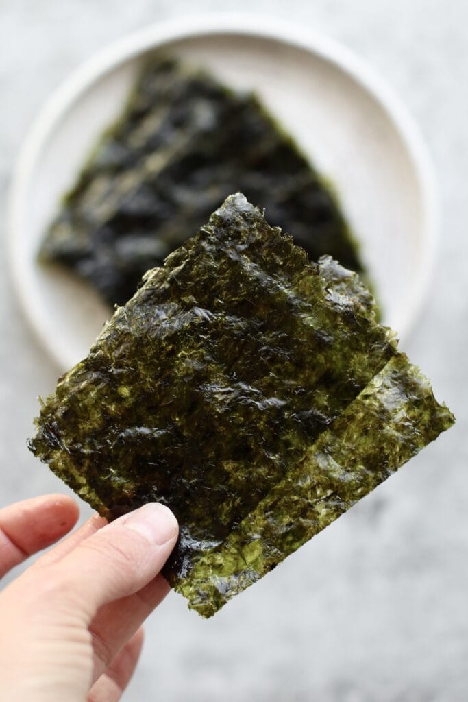 Two small sheets seaweed snacks being held up
