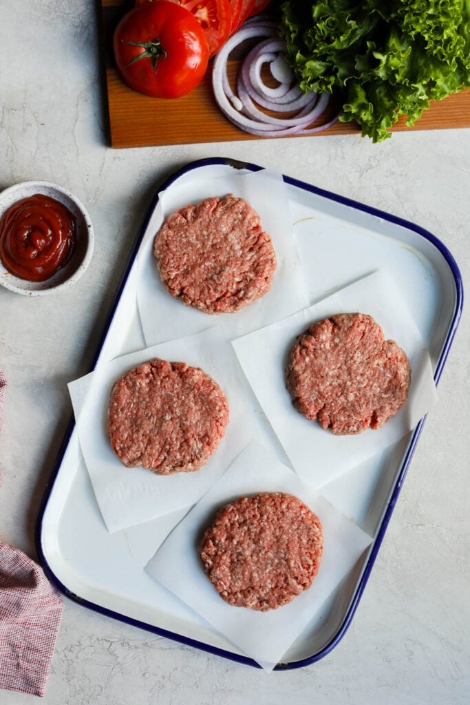 Overhead view grass fed burgers, raw on parchment paper squares