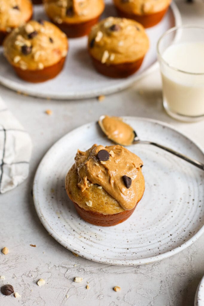 Single peanut butter protein muffin on stone plate topped with peanut butter and chocolate chips