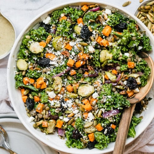Overhead view lentil salad with roasted vegetables in serving bowl topped with feta cheese