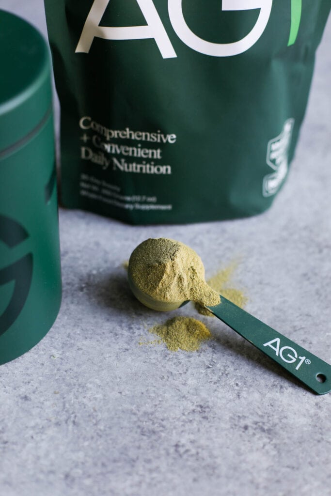 A rounded scoop of AG1 green supplement powder.