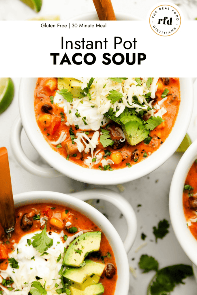 White bowls filled with instant pot taco soup topped with sour cream, cheese, cilantro, and avocado chunks