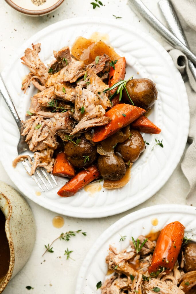 A plate of Crock Pot Pork Roast, potatoes, and carrots drizzled in gravy. 