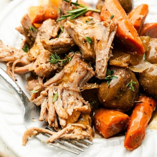 A plate of crock pot pork roast with carrots and potatoes.