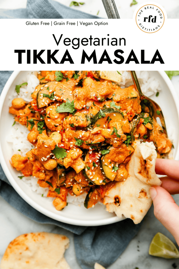 Overhead view vegetarian tikka masala served over rice in bowl with naan being dipped in tikka masala