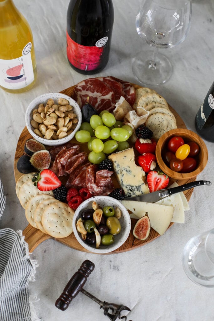 Overhead view charcuterie board with bottles of wine around the board