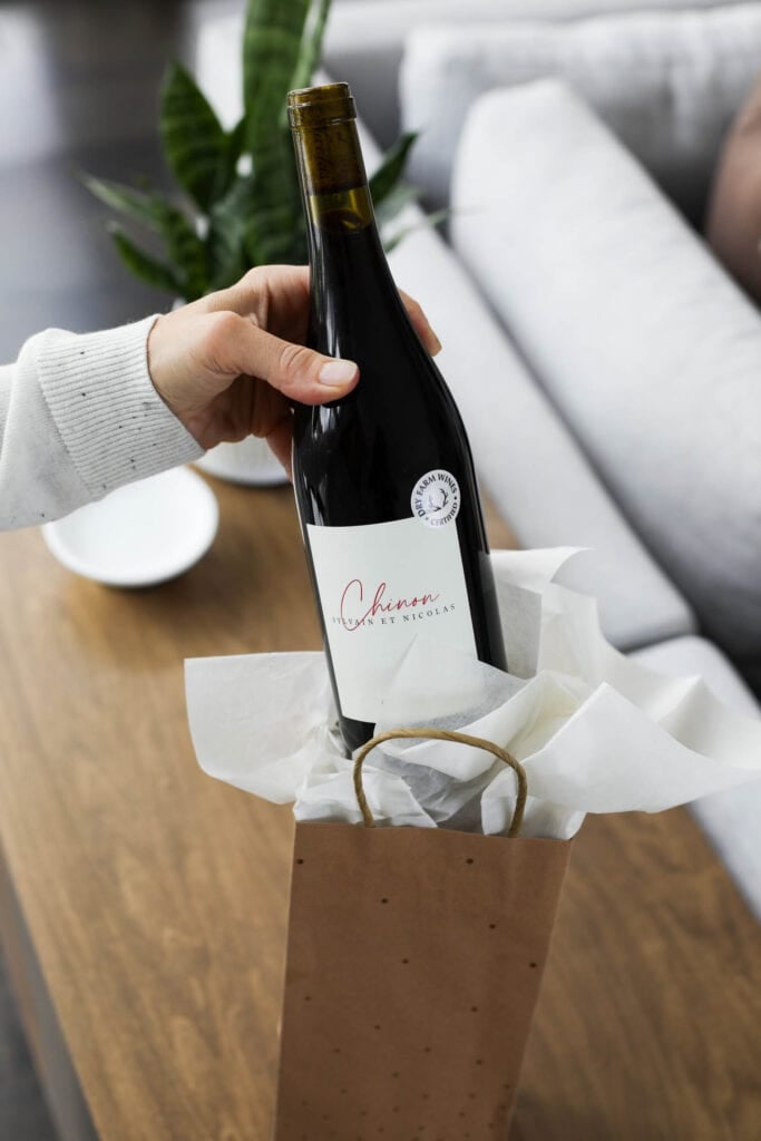 A women removing a bottle of wine with a Dry Farm Wines label from gift bag