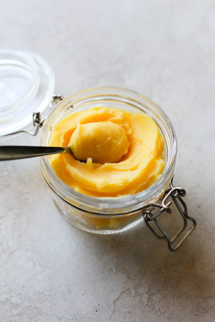 A jar of ghee with a full spoon ready to be taken out. 