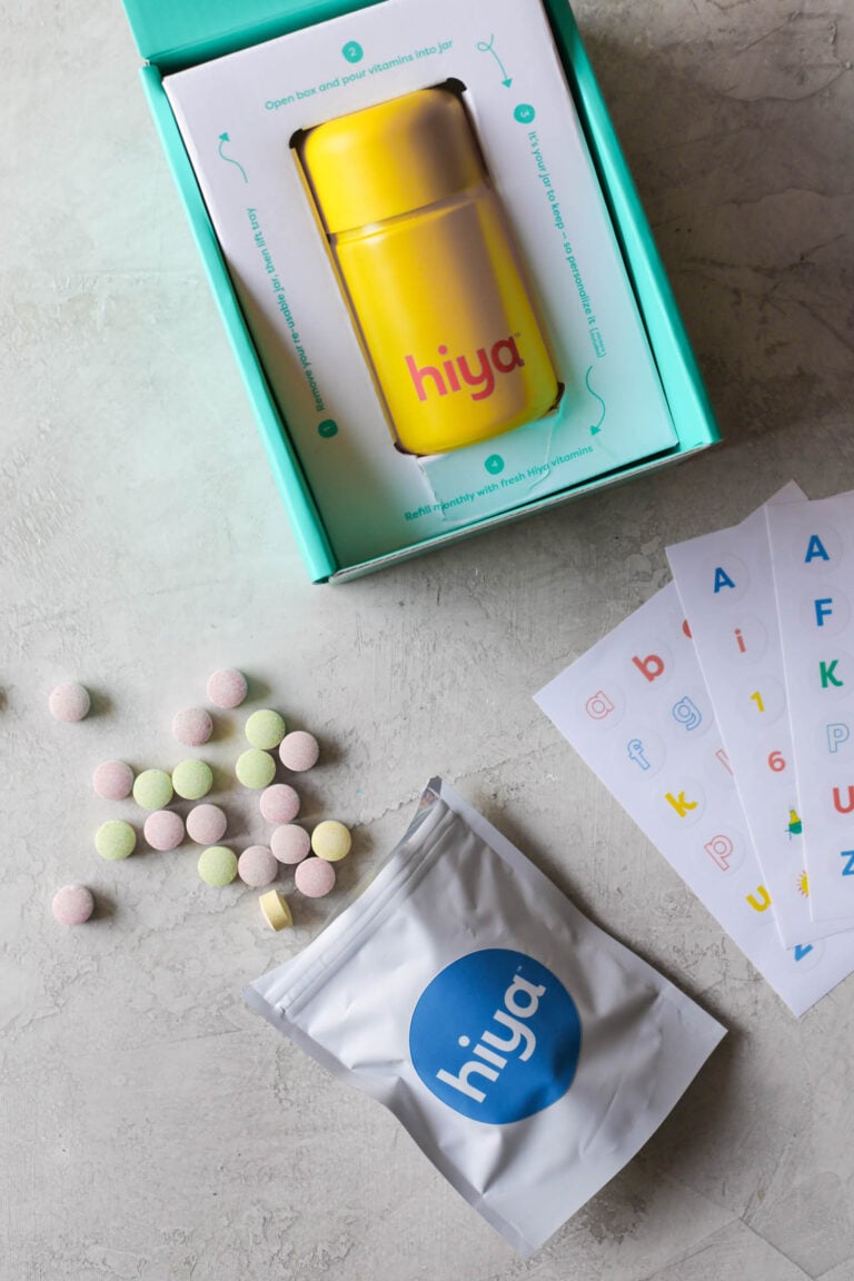 Overhead view Hiya kids vitamins in packaging with refill packet in front, open with chewable tables spilling out