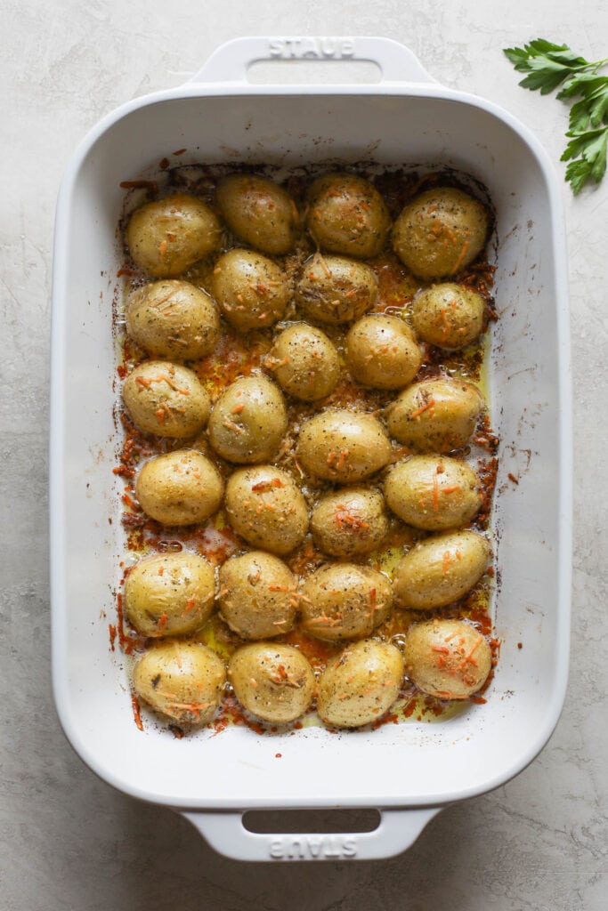 Overhead view oven baked Parmesan crusted potato halves in white baking dish
