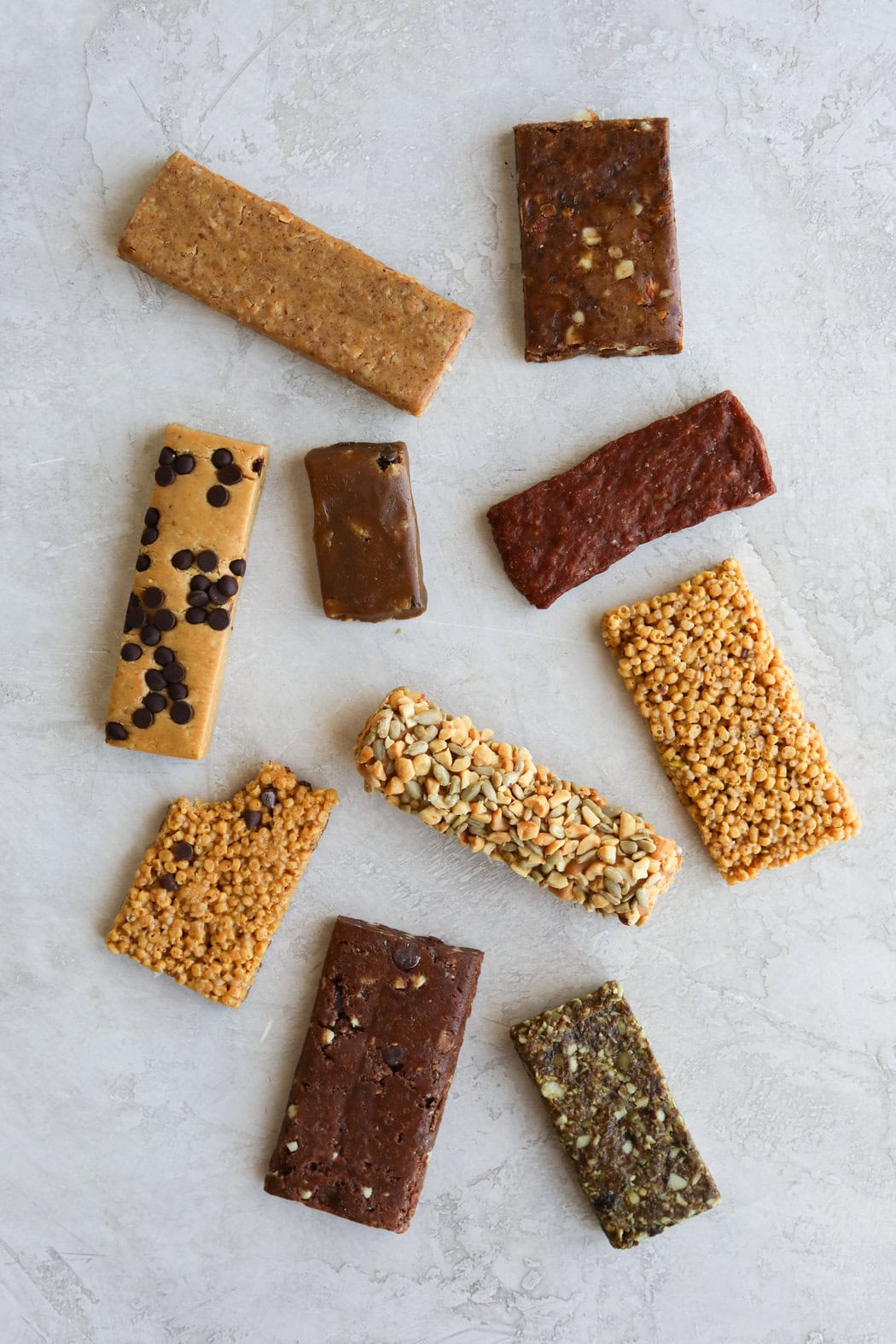 Overhead view of a variety of unwrapped protein bars in different sizes and textures. 