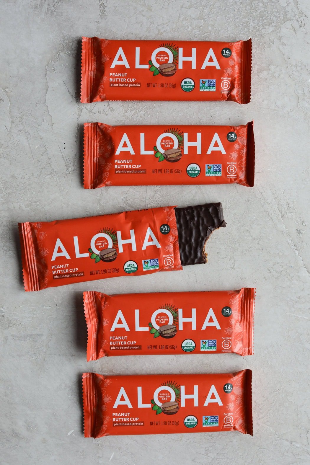 Overhead view of aloha protein bars in a row with one opened to show texture. 