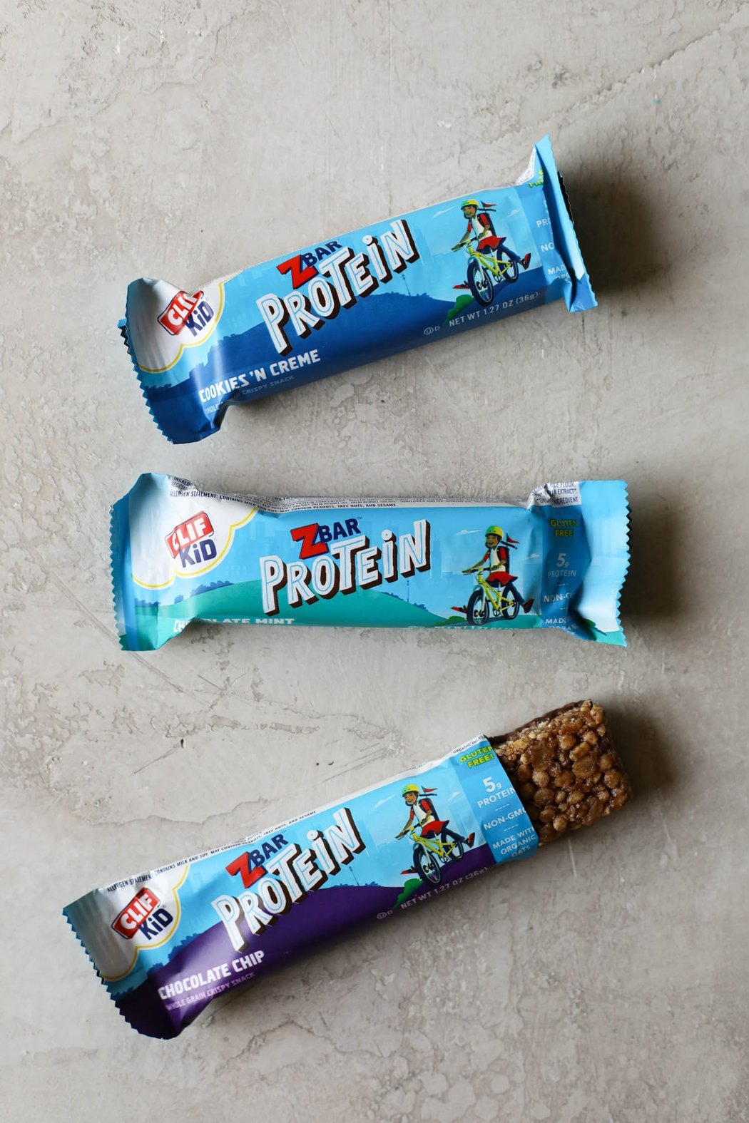 Overhead view of kids Zbar protein bars in a row with one opened to show texture.