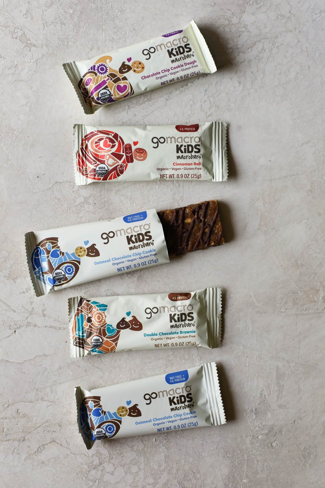 Overhead view of go macro Kids protein bars in a row with one opened to show texture. 