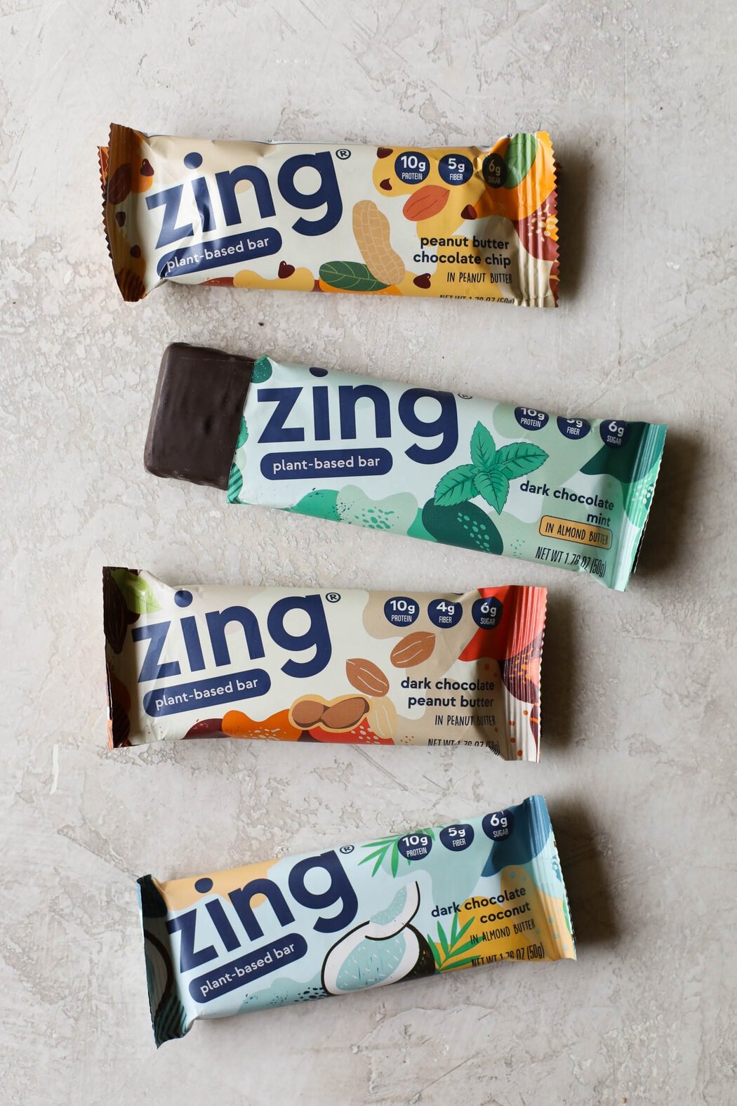 Overhead view Zing protein bars on countertop with one package open to show inside protein bar