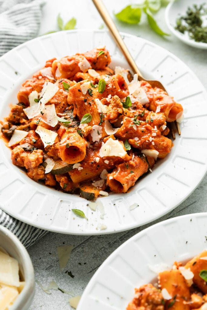 Rigatoni topped with Parmesan cheese in white bowl