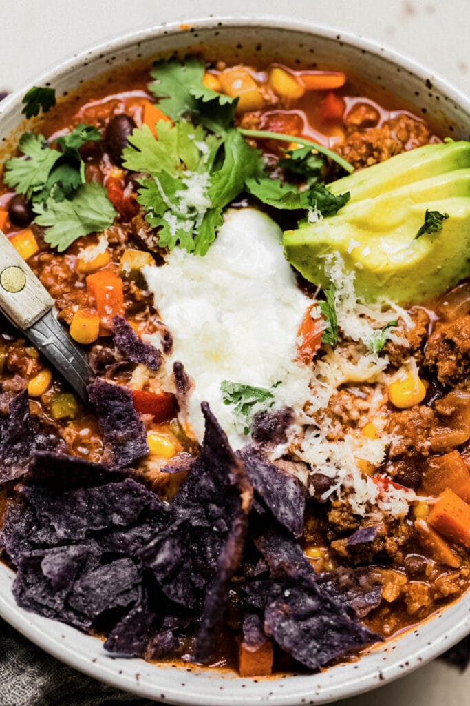 A close up of a bowl of healthy turkey chili so you can see the texture and all of the yummy toppings.