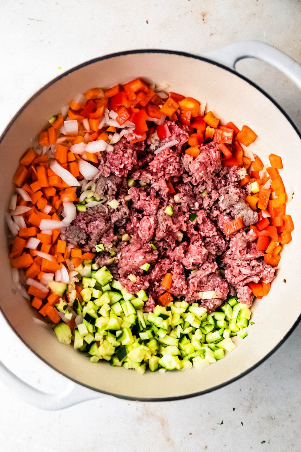 Ground turkey and chopped bell peppers, garlic, onion, carrots, and zucchini after a quick sauté to make healthy turkey chili.