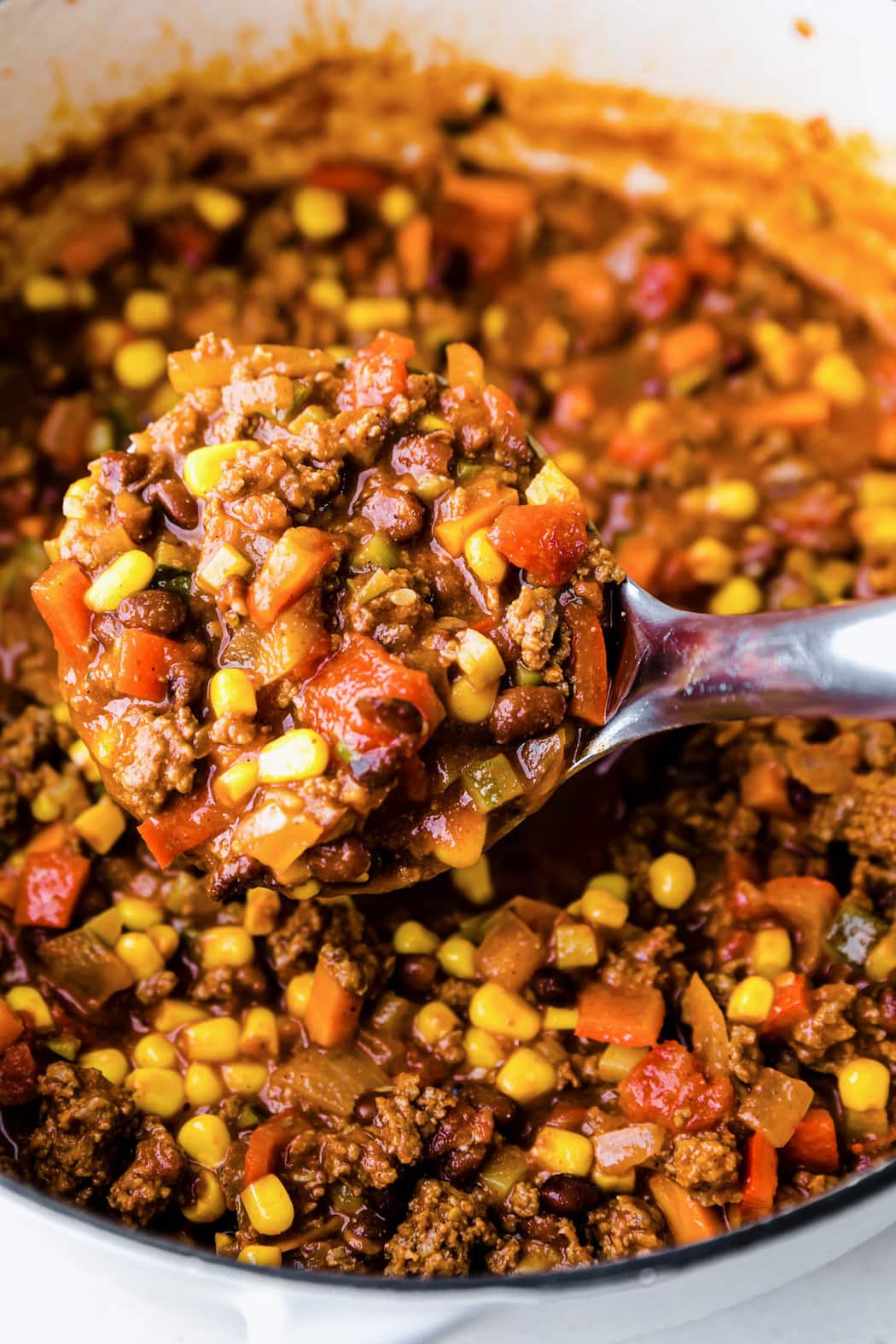 A ladle filled with veggie loaded turkey chili over a pot of chili