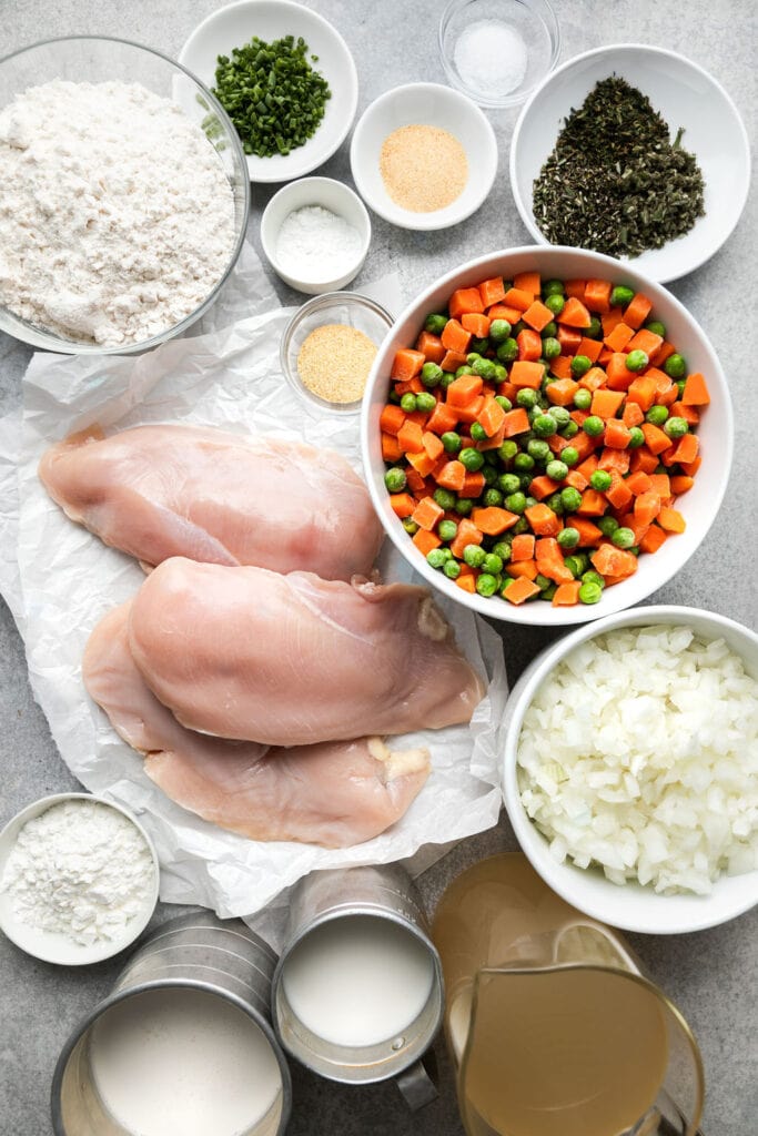 The ingredients for Chicken Dumpling Soup, including chicken breast, diced carrots and peas, spices, diced onion, flour, and heavy cream. 