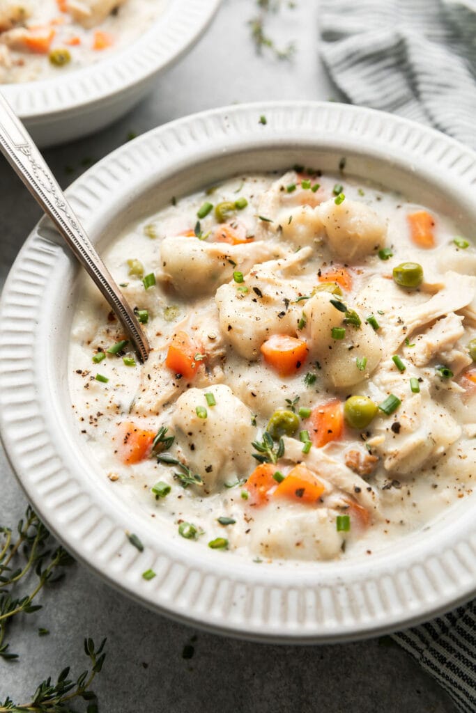 A delicious bowl of creamy Chicken Dumpling Soup topped with fresh chopped herbs like thyme and chives too. 