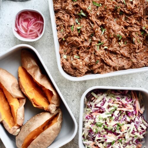 Overhead view Caraway food storage containers filled with baked sweet potatoes, pickled onions, coleslaw, and shredded pork