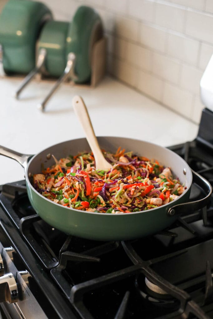 Caraway skillet in green on a stovetop filled with chicken pad thai.
