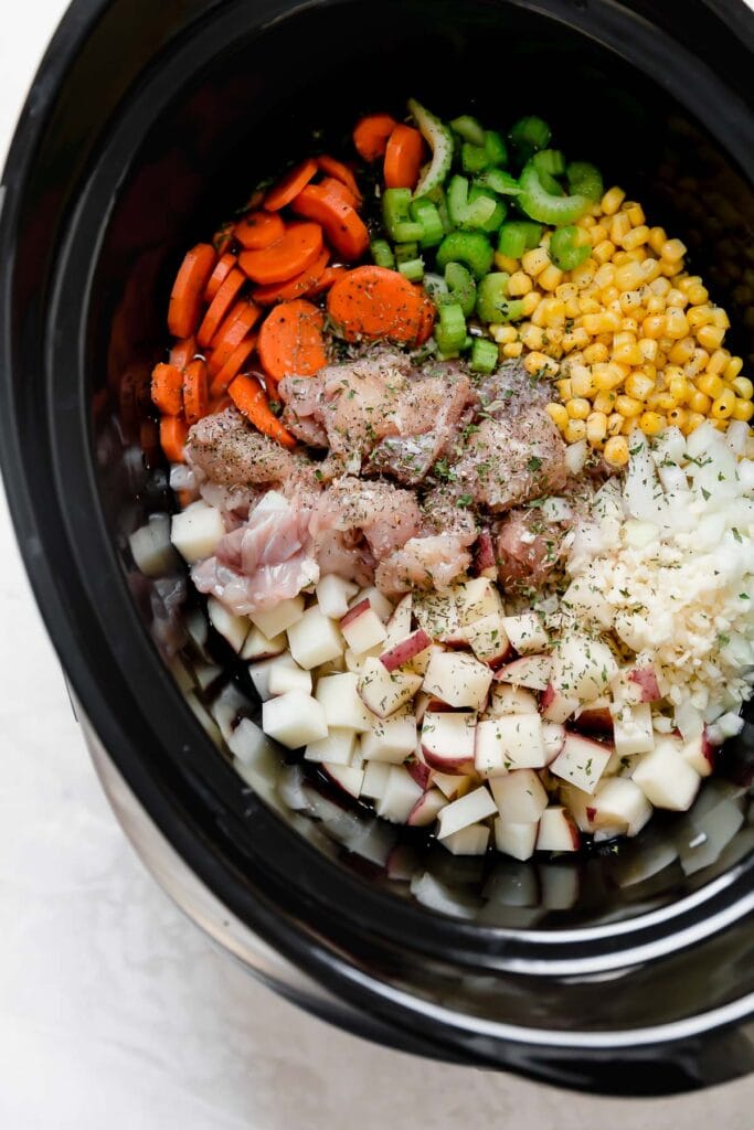 All ingredients for chicken corn chowder in a black slow cooker ready to be stirred together