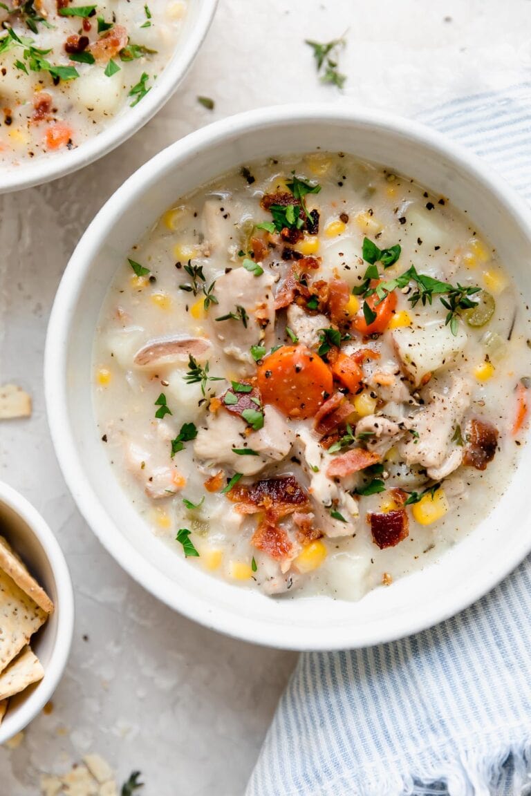 Overhead view white bowl filled with creamy chicken corn chowder topped with crisp cooked bacon pieces.