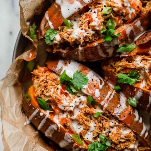 Close up overhead view buffalo chicken stuffed baked sweet potatoes with ranch and hot sauce drizzled on top