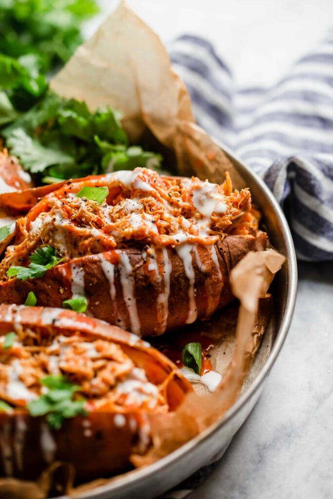 Side view buffalo chicken stuffed baked sweet potato drizzled with ranch