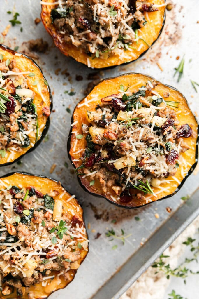 Overhead view baked acorn squash, stuffed with a mixture of sausage, apple, cranberries, pecans, spinach and topped with Parmesan cheese