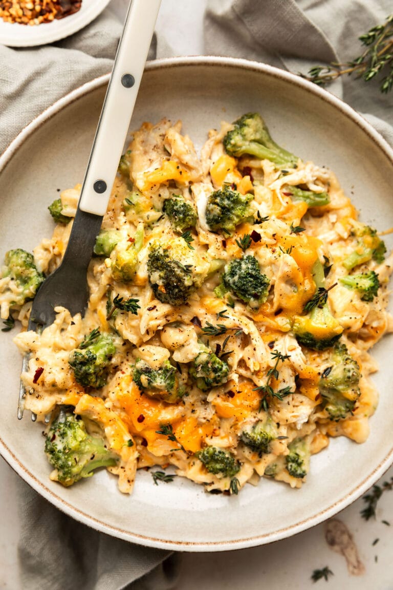Overhead view serving of cheesy chicken skillet with broccoli and rice on plate with fork